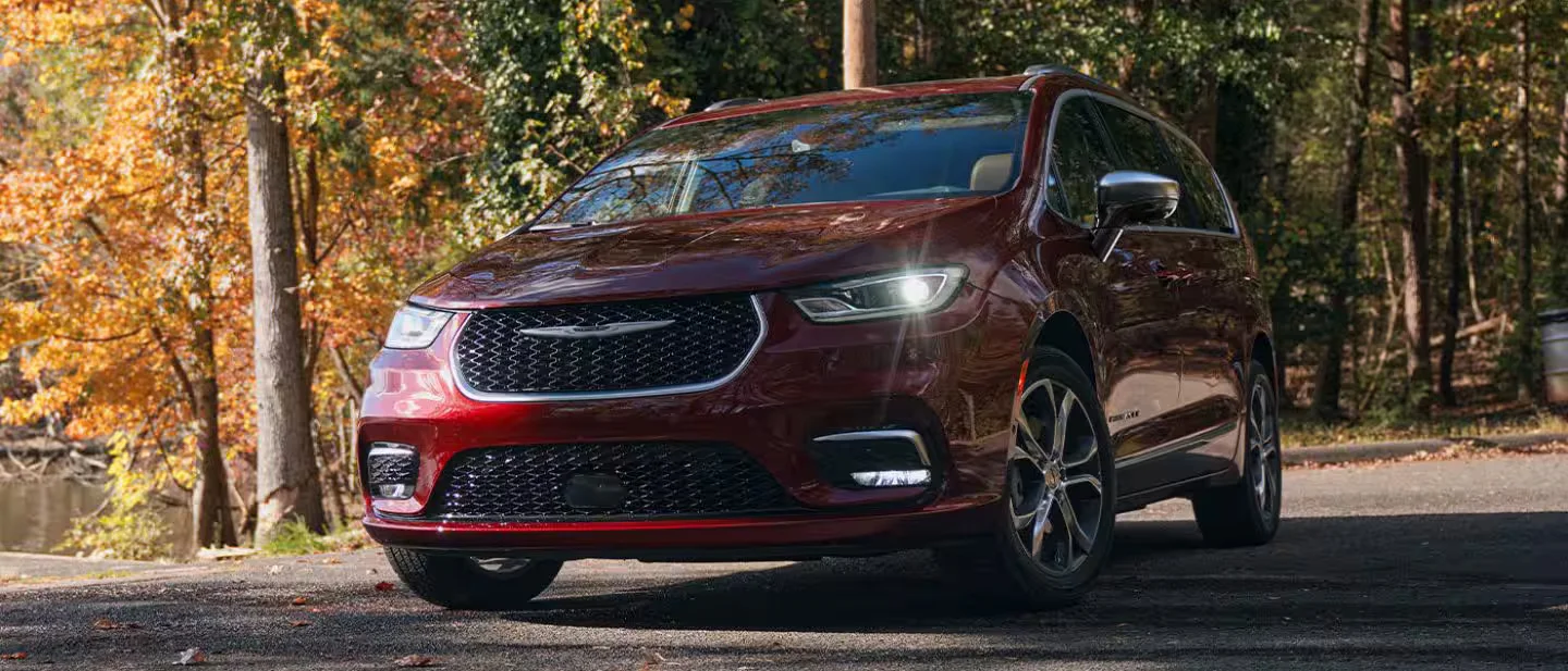 2026 Chrysler Pacifica red minivan parked near autumn trees in front three-quarter exterior view