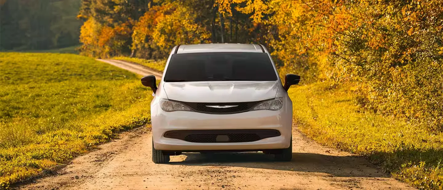 2026 Chrysler Voyager white minivan on an autumn lane, front view.
